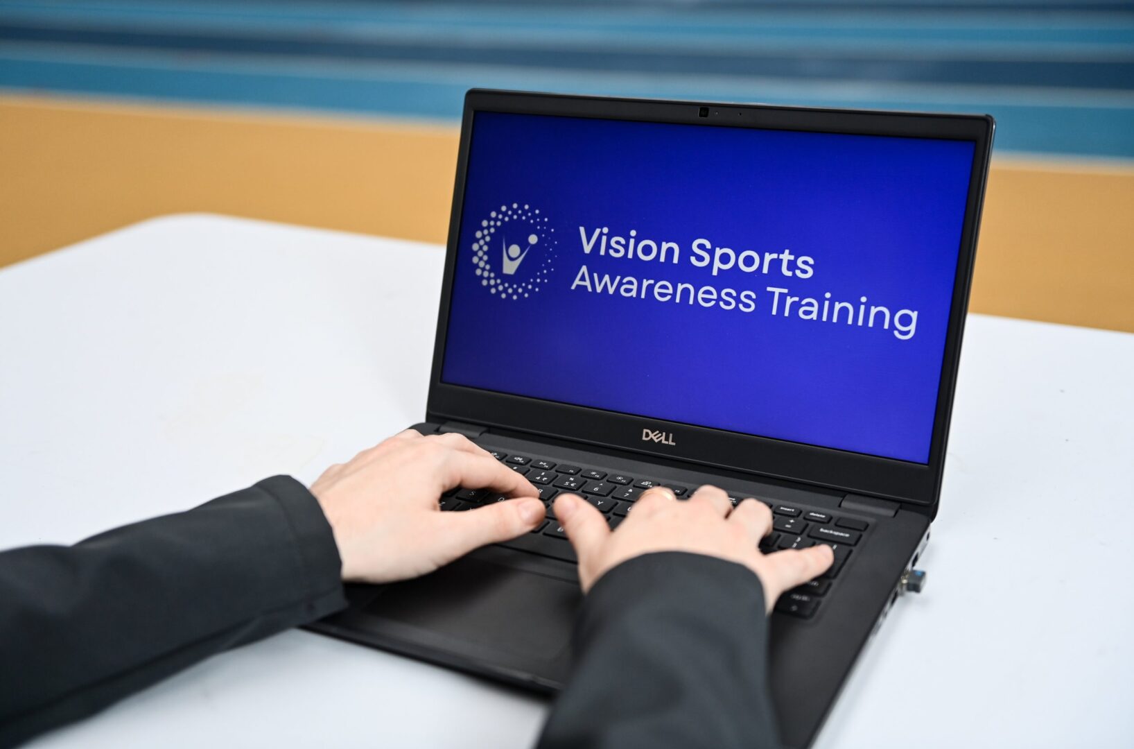 Photo of hands of person on laptop with words Vision Sports Awareness Training on a blue screen.
