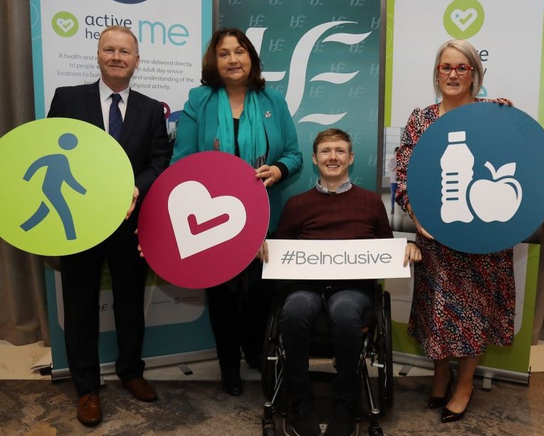 Photo of a man standing, woman, man in wheelchair and woman, all holding Active Healthy Me logos